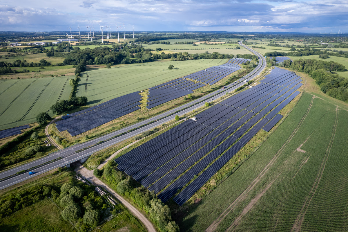 Luftaufnahme eines Solarparks entlang einer Autobahn.